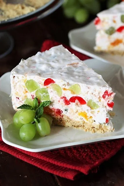Cheesecake topped with colorful fruit salad on a white plate